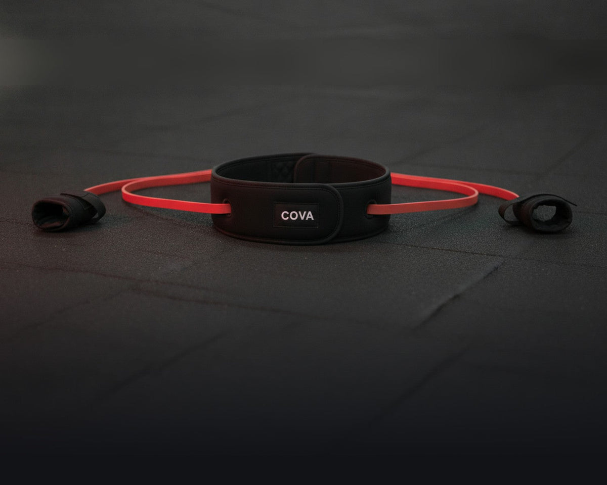 The COVA belt, red bands and wrist cuffs on a dark gym floor