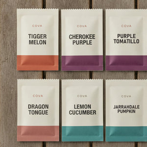 Six labeled COVA seed packets laid out on a wooden table