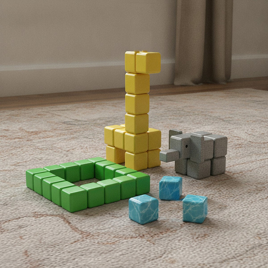 A giraffe and an elephant with a pen built from cubes on a rug
