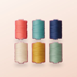 Six spools of thread in coral, teal, navy, cream, mustard and sage