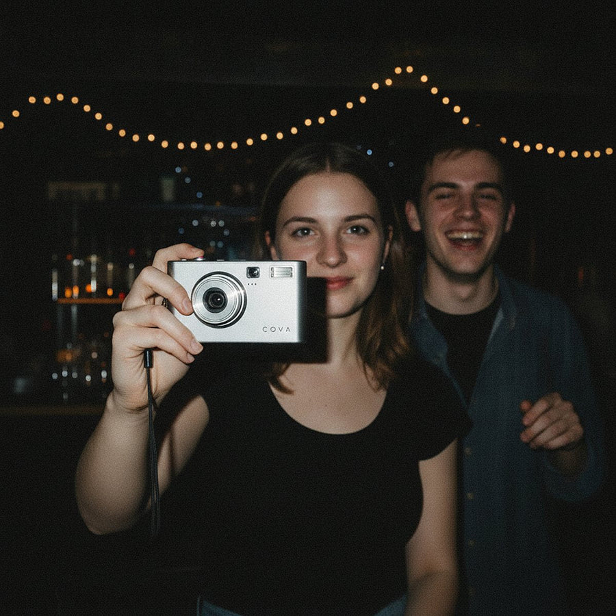 A woman taking a flash photo with the COVA camera at night